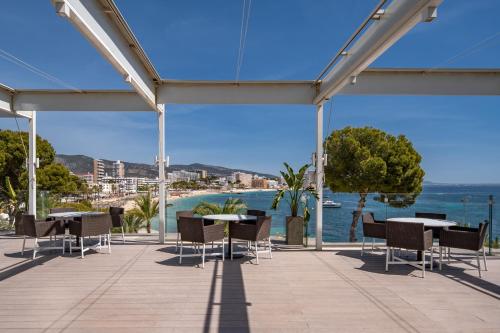 a patio with tables and chairs and a view of the water at Meliá Calviá Beach in Magaluf
