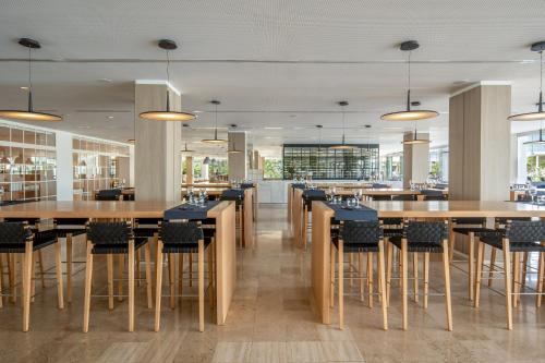 a restaurant with wooden tables and chairs and windows at Meliá Calviá Beach in Magaluf