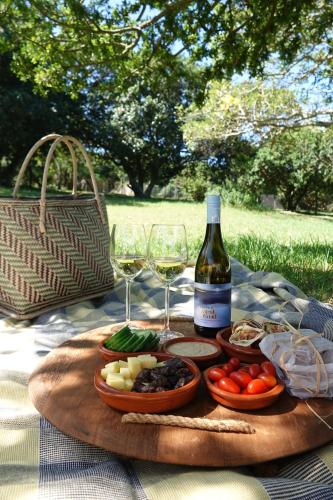 a table with a plate of food and a bottle of wine at Soutelande Country Stay - Close to 1#Beach in PE in Port Elizabeth