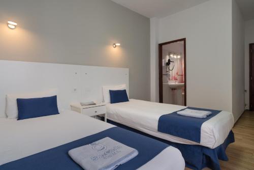 een hotelkamer met 2 bedden en een spiegel bij Hostal San Ginés in Arrecife