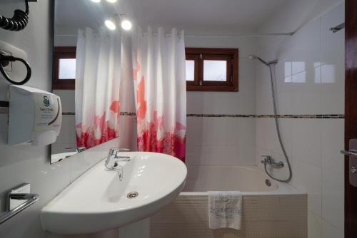 a white bathroom with a sink and a bath tub at Hostal San Ginés in Arrecife