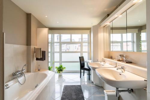 W łazience znajdują się 2 umywalki, wanna i tubermot. w obiekcie Maas&Mechelen B&B Massage & Wellness w mieście Maasmechelen