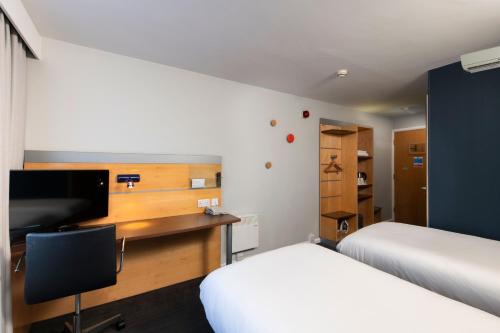 um quarto com 2 camas e uma secretária com uma televisão em Holiday Inn Express Leeds City Centre, an IHG Hotel em Leeds