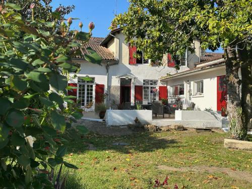 a white house with a red door and a yard at La Maison Florence in Mont-de-Marsan