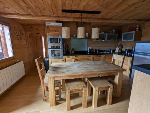 una cocina con mesa de madera y sillas en una cabaña en Bas de chalet au coeur des Aravis, entre lac et montagne, en Saint-Jean-de-Sixt