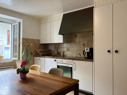 uma cozinha com armários brancos e uma mesa de madeira em La Lanterne em Sierre