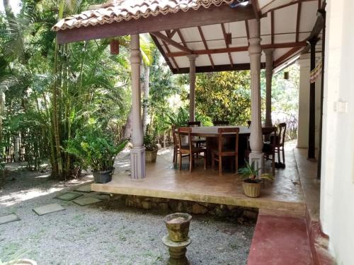 a patio with a table and chairs under a pergola at Rock house in Hiriketiya