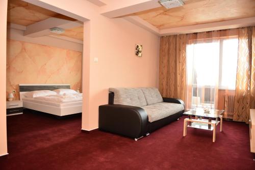 a bedroom with a bed and a couch and a table at Hotel Ďumbier in Brezno