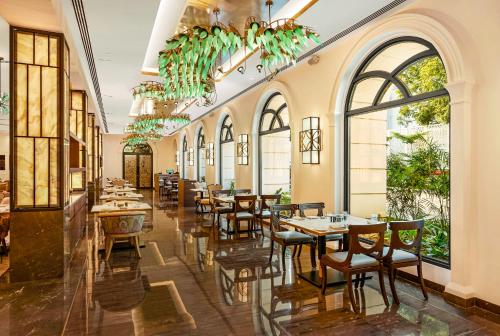 a restaurant with tables and chairs and large windows at Radisson Blu Hotel & Suites GRT Chennai in Chennai