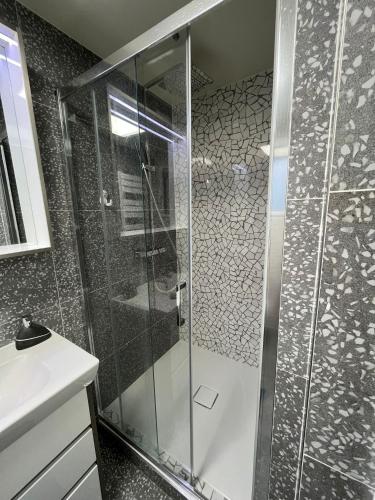 une douche avec une porte vitrée dans une salle de bain dans l'établissement SCI Slama FAMILY, à Livry-Gargan