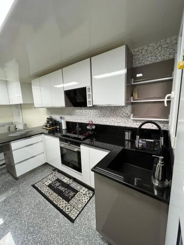 une cuisine avec des armoires blanches et un comptoir noir dans l'établissement SCI Slama FAMILY, à Livry-Gargan