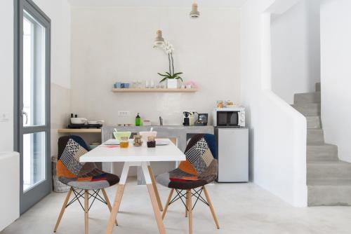 a white kitchen with a white table and chairs at LAGADI SUITES by K&K in Mesaria