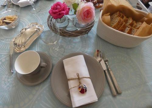 uma mesa com um prato de pão e uma taça de rosas em La Maison Florence em Mont-de-Marsan