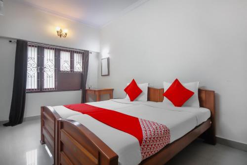 1 dormitorio con 1 cama grande con almohadas rojas en OYO Home Tree Service Apartment Near Saravana Stores T Nagar, en Chennai