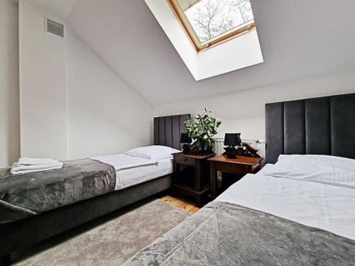 a bedroom with two beds and a desk and a skylight at Karczma Ostoya in Jasionka