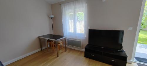 ein Wohnzimmer mit einem Tisch, einem TV und einem Fenster in der Unterkunft Belle maison indépendante 4 pers avec terrasse in Rueil-Malmaison