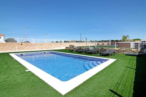a swimming pool on a lawn with a table and chairs at Villa Flora in Algoz