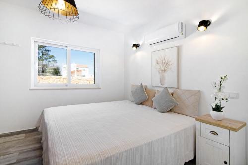 a white bedroom with a bed and a window at Villa Flora in Algoz