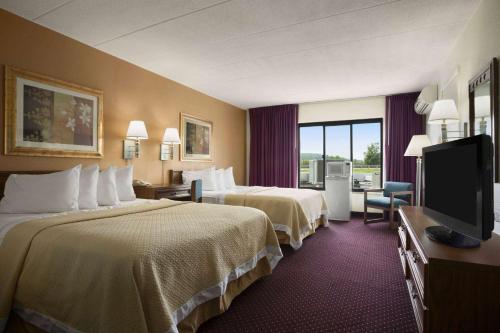 a hotel room with two beds and a flat screen tv at Ramadaby Wyndham Pittsburgh-New Stanton in New Stanton