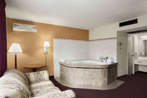 Habitación de hotel con bañera y sofá en Ramadaby Wyndham Pittsburgh-New Stanton en New Stanton