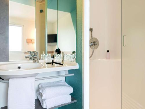 a bathroom with a sink and a mirror at ibis budget Freiburg Sued in Freiburg im Breisgau