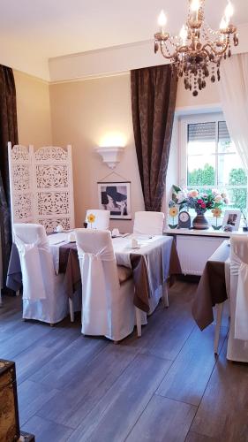 een eetkamer met witte tafels en stoelen en een kroonluchter bij Garni Villa Tyrol - Adults Only in Merano