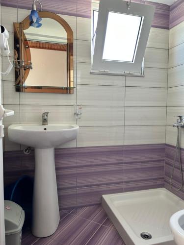 La salle de bains est pourvue d'un lavabo, d'un miroir et de toilettes. dans l'établissement Guesthouse Dollomaja Ksamil, à Ksamil
