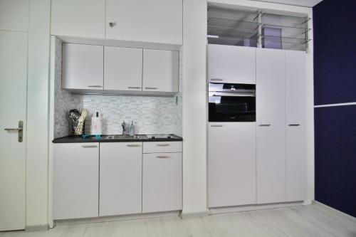 a white kitchen with white cabinets and a sink at Ferien am Luganer See mit Seesicht in Bissone