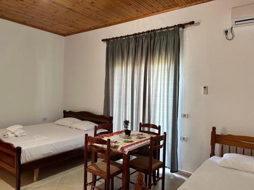 a bedroom with two beds and a table and chairs at Guesthouse Dollomaja Ksamil in Ksamil