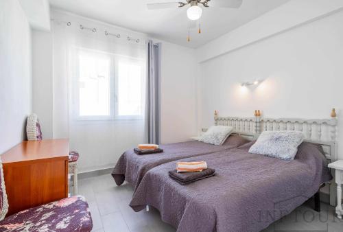 1 Schlafzimmer mit 2 Betten, einem Tisch und einem Fenster in der Unterkunft Inftour Primavera Apartamento in Calpe