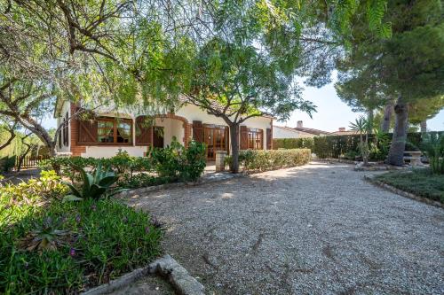 a house with trees and a gravel driveway at Hauzify I Casa Cardona in Les tres Cales