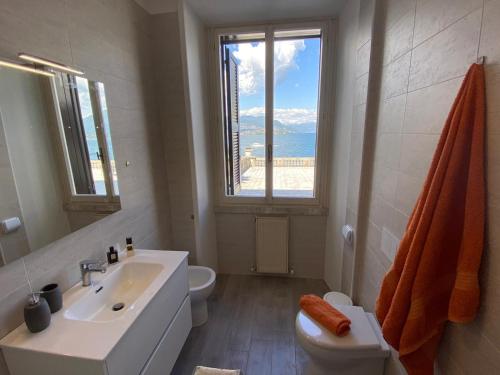 uma casa de banho com um lavatório, um WC e uma janela. em Wonderful Stresa apartment em Stresa