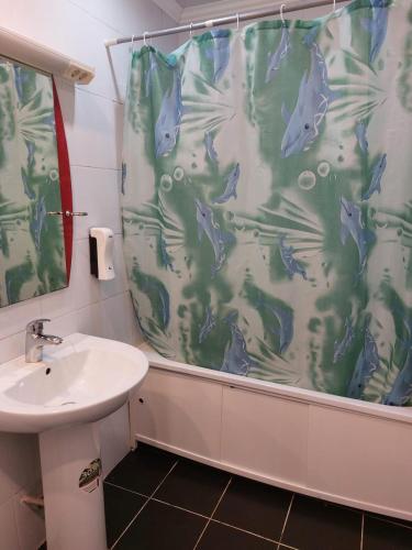 a bathroom with a shower curtain and a sink at Victoria Hotel in Aktau