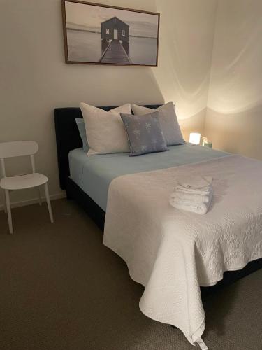 a bedroom with a bed with a white blanket and a chair at Walk to P!NK & Palmer B&B - U21 in Townsville