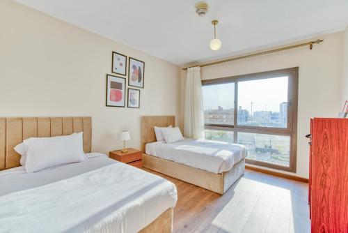 a bedroom with two beds and a large window at LOFTS by Elegant Hospitality in Cairo