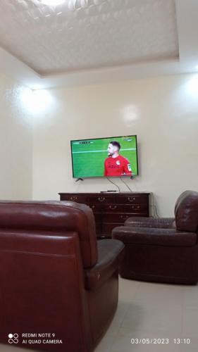 sala de estar con sofá y TV en la pared en Villa meublée à Sendou, en Siendou