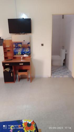 ein Wohnzimmer mit einem Schreibtisch und einem TV in der Unterkunft Villa meublée à Sendou in Siendou