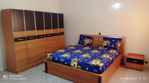 1 dormitorio con 1 cama y armario de madera en Villa meublée à Sendou, en Siendou