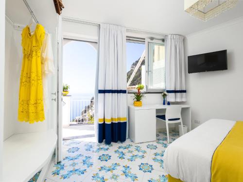 Blue Waves - De Vivo Realty Positano في بوسيتانو: غرفة نوم بها سرير ومكتب ونافذة