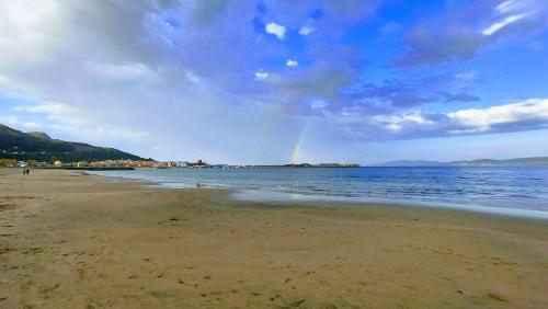 a rainbow in the sky over a beach at Apartamento La Ilusión - Cariño in Cariño