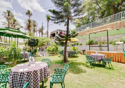 a patio with tables and chairs and a building at Hari Niwas - A Boutique Garden Resort Mount Abu in Mount Ābu
