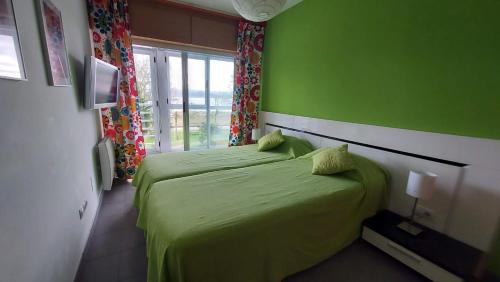 Dormitorio verde con cama y ventana en Apartamento La Ilusión - Cariño, en Cariño