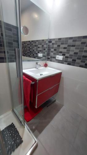 uma casa de banho com um lavatório vermelho e um chuveiro em Apartamento La Ilusión - Cariño em Cariño