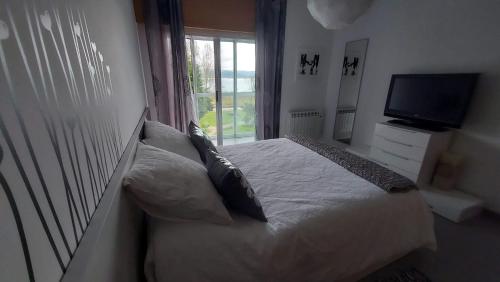 a bedroom with a bed with a television and a window at Apartamento La Ilusión - Cariño in Cariño