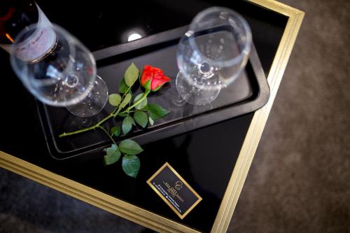 a table with wine glasses and a red rose on it at Hotel CITY Sandanski in Sandanski