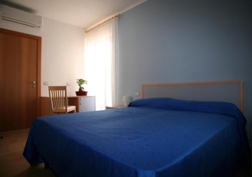 - une chambre avec un lit bleu, une chaise et une fenêtre dans l'établissement B&B Virolì, à Vieste
