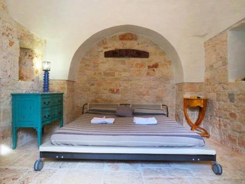 Cama en habitación con pared de piedra en trullo fino, en Cisternino