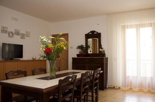 - une table à manger avec un vase de fleurs dans l'établissement B&B Virolì, à Vieste