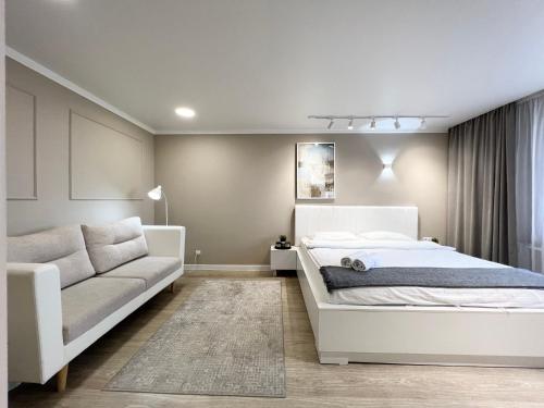 1 dormitorio con cama blanca y sofá en Luxury apartments en Pavlodar