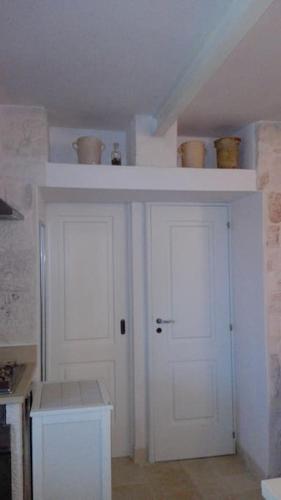 a kitchen with a white cabinet and a white door at trullo fino in Cisternino